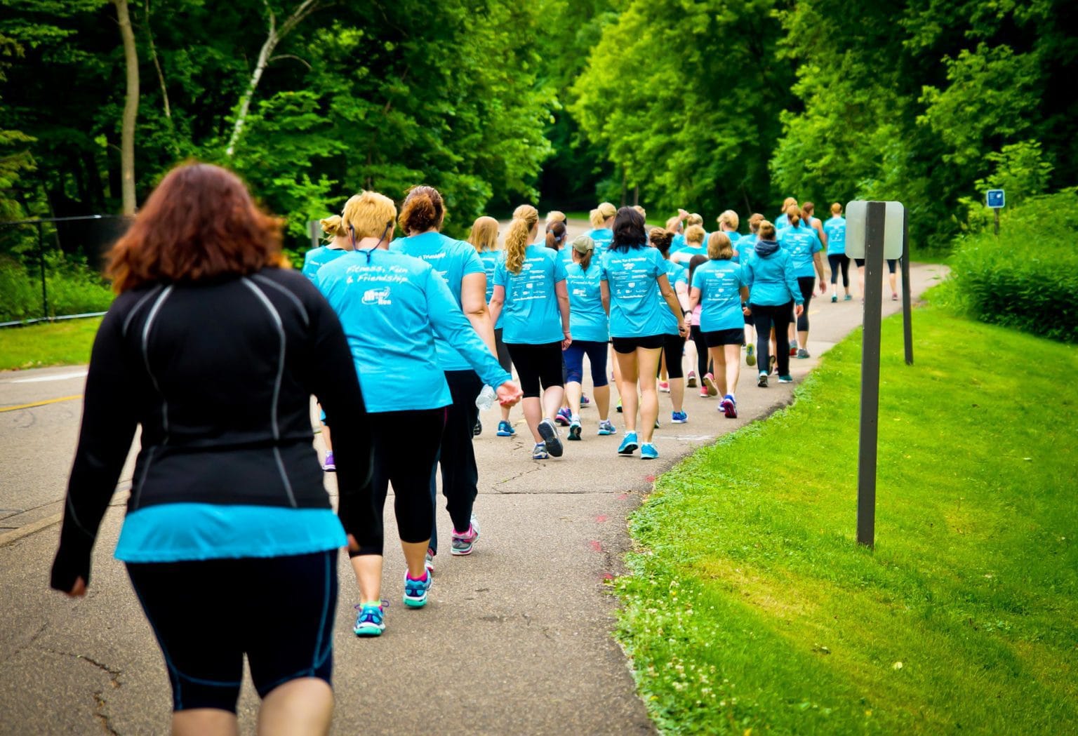 A large group of Moms on the Run members in teal shirts, from behind