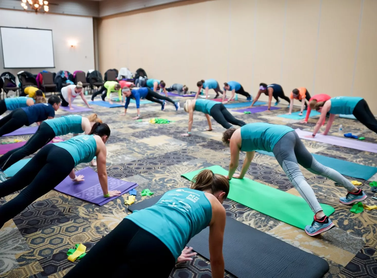 A group of women in a conference room doing pushups on yoga mats