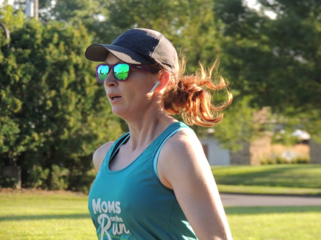 Coach Dana from Eau Claire running in a hat, ear buds and sunglasses