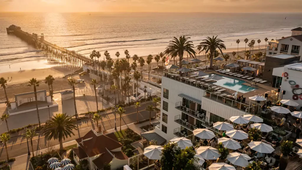 View of destination race hotel from above - on beach, rooftop pool, palm trees and sun setting,