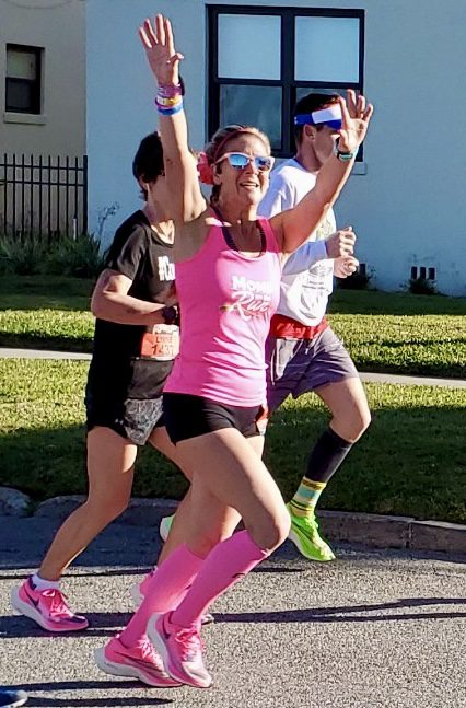 Franchise Owner Amy waves while running a race