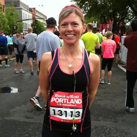 Charlyn, owner of Cottage Grove Moms on the Run, stands on a crowded street wearing a race bib