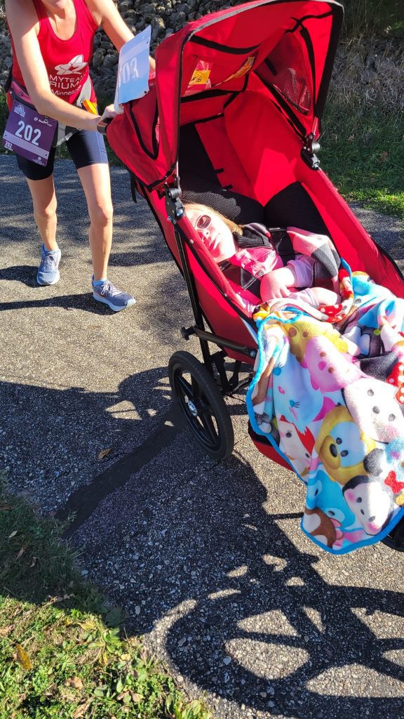 runner in red tank pushing a jogging stroller uphill