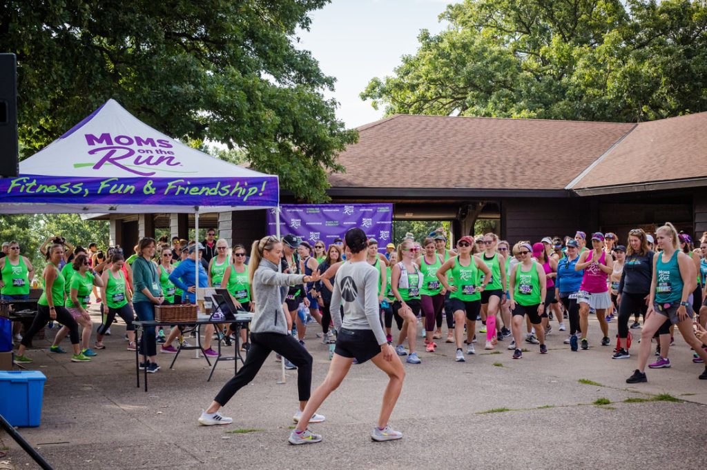 Carrie Tollefson and a Summit Orthopedics MD leading a group of women in warm ups prior to the Moms on the Run annual race. Summit is a sponsor of the race.