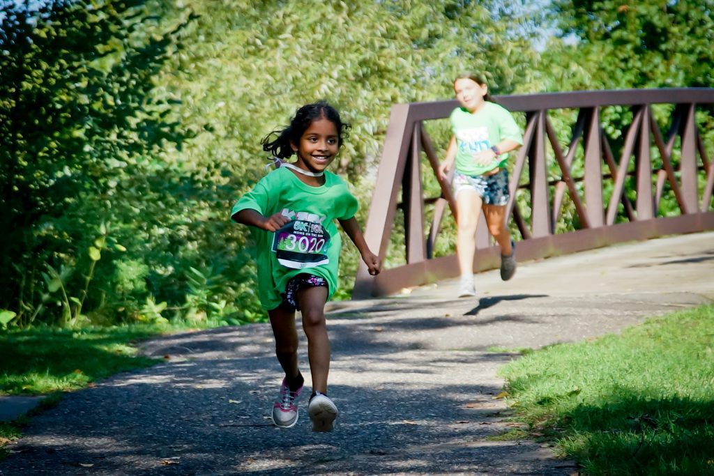 A CHILD with a race bib running on a path