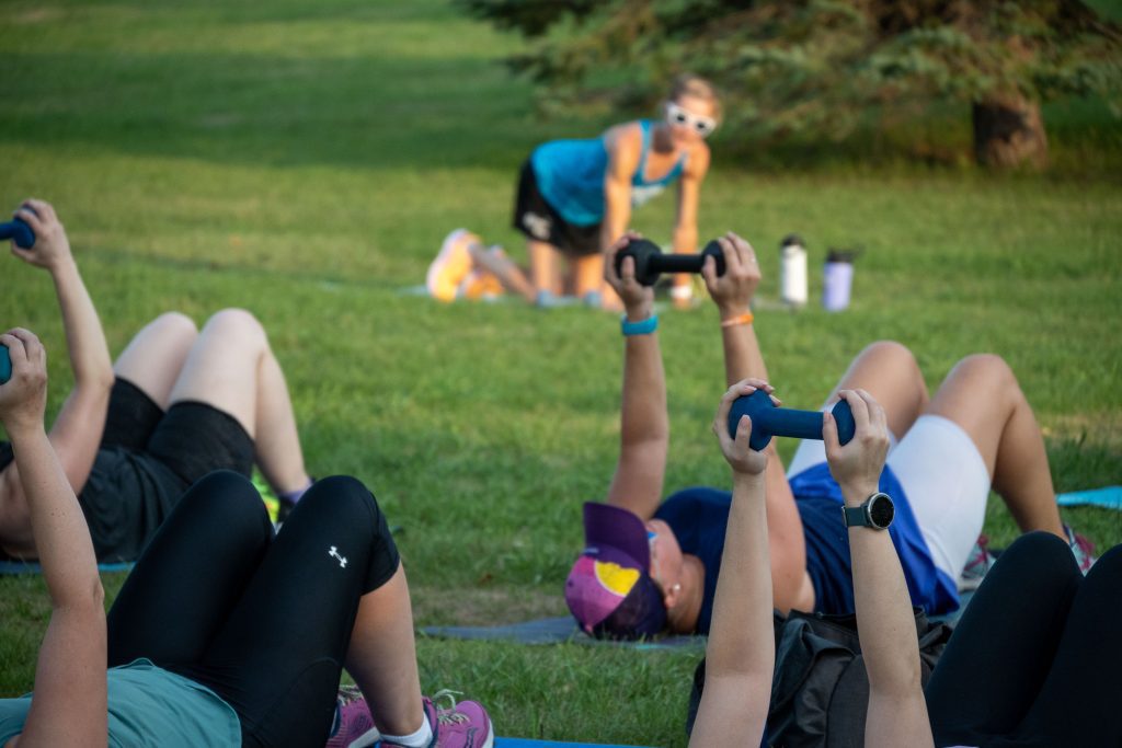 Women laying on ground holding weights over their torsos