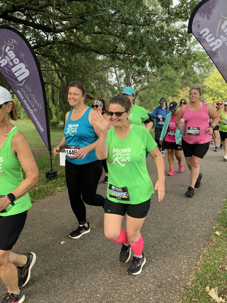 Woman waving while running the MOTR 5K/10K race