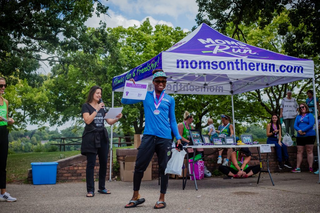 MOTR member holding an award certificate in front of a MOTR tent