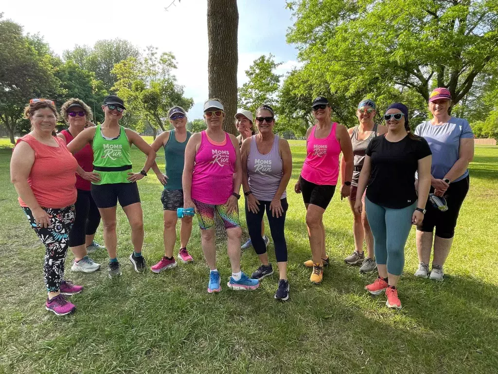 11 Lakeville-Burnsville Moms on the Run members standing by a tree smiling