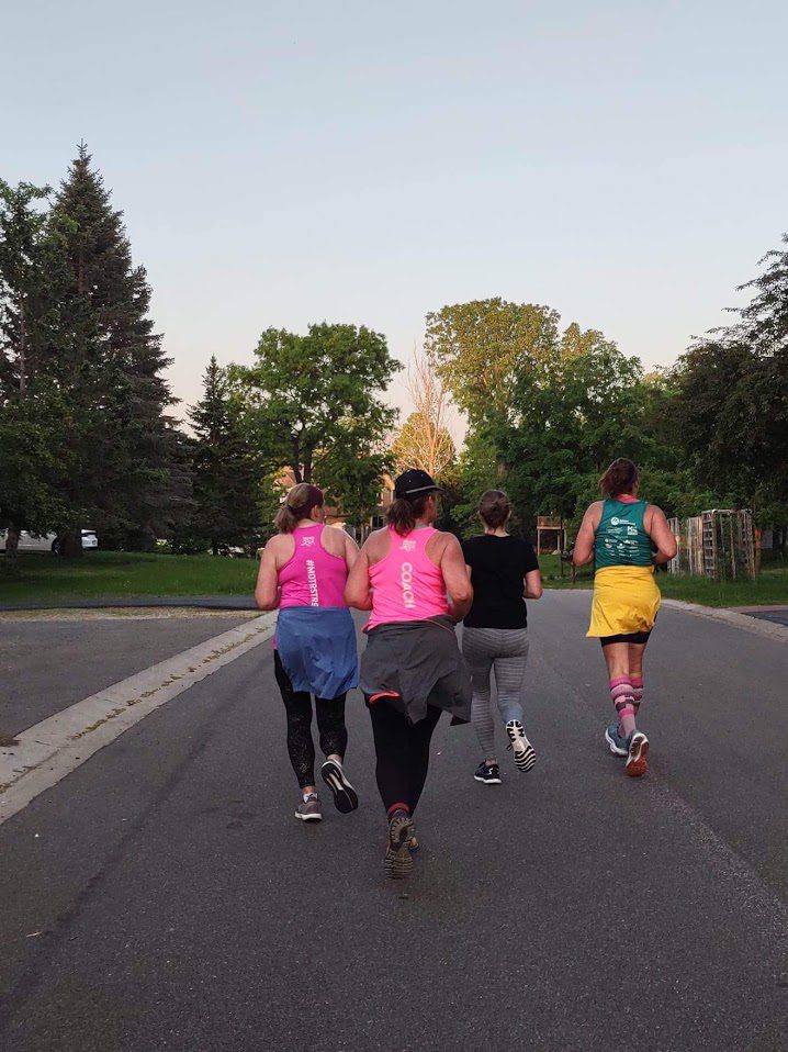A coach and three members of the Burnsville-Lakeville Moms on the Run are running down a street