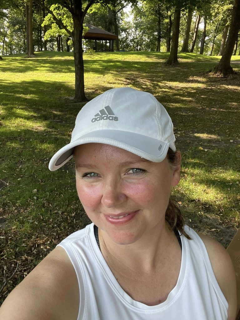 Franchise owner Karey wearing white hat and tank top outside