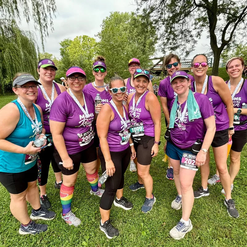 Female runners in purple shirts with medals standing in a group
