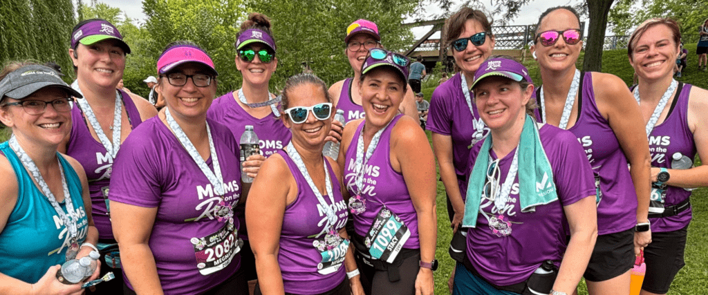 women runners in purple tanks smiling with medals