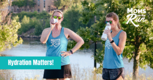 two female runners standing and drinking water bottles