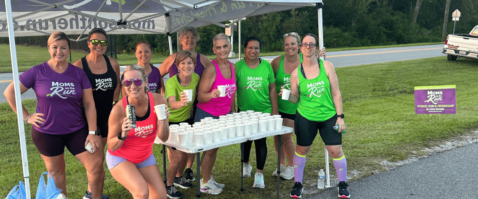 women in multi-colored running tanks at water station